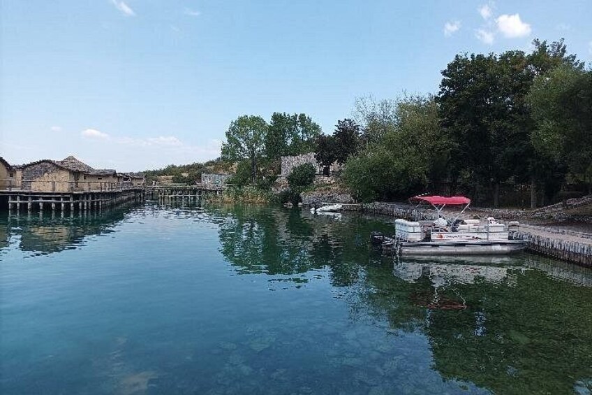 Un río tranquilo con un muelle, un bote con toldo rojo y edificios a lo largo de la orilla. 4