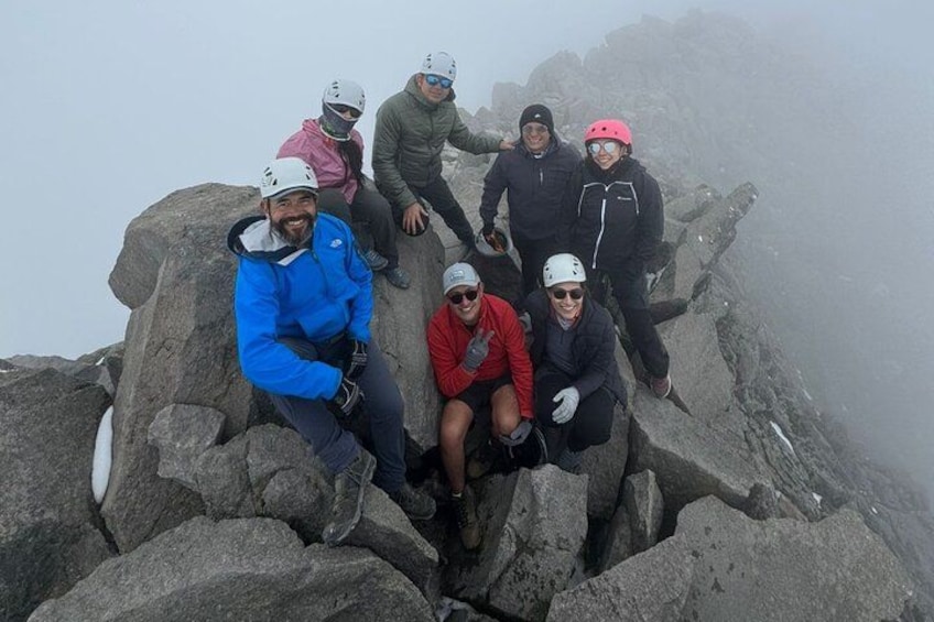Un grupo de personas sentadas en la cima de una montaña rocosa. 3