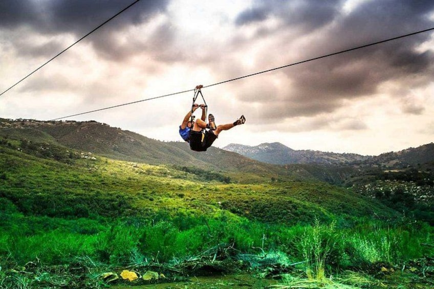 A person suspended in mid-air, performing an acrobatic stunt on a cable. 1