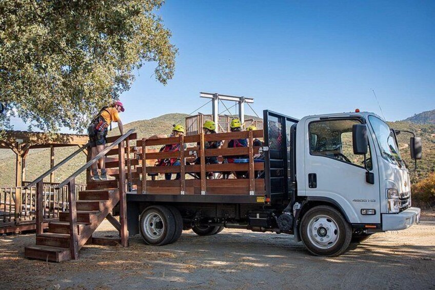A white truck parked on a dirt road with a wooden ramp leading up to a wooden platform. 4