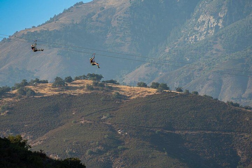 A mountainous landscape with power lines and two helicopters in flight. 3