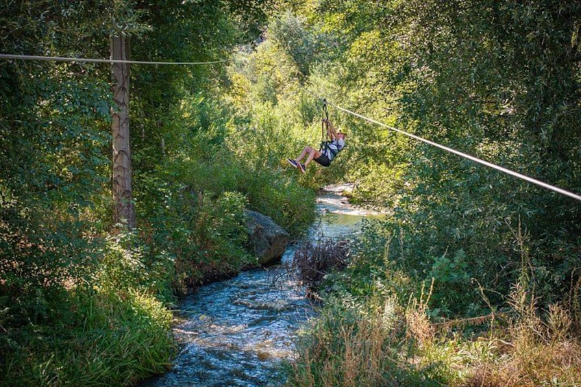 A person zip-lining over a river surrounded by dense greenery. 2