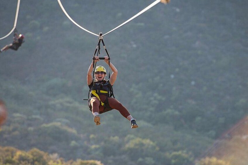 A person suspended in mid-air, attached to a harness and ropes, with a mountainous landscape in the background. 3
