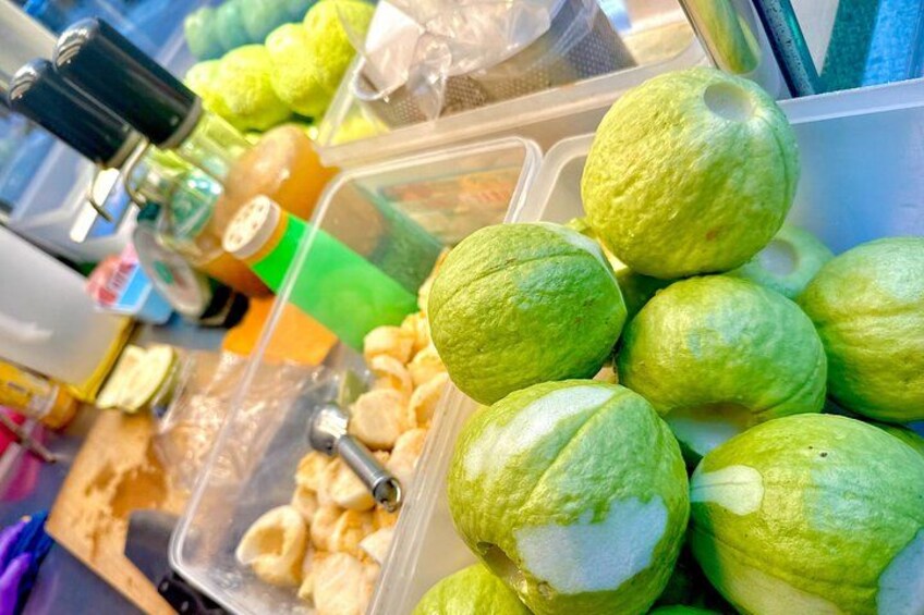 A container with green fruits, possibly guavas, and a plastic container with what appears to be dried snacks. 4