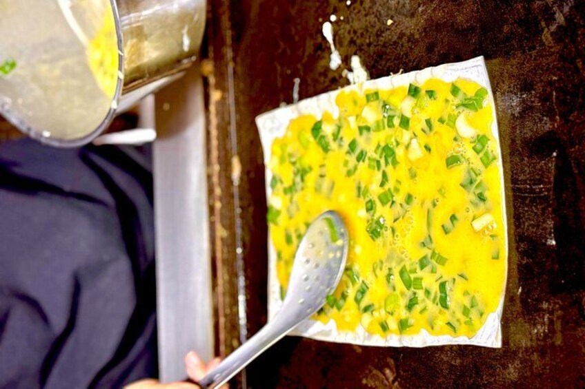 A person pouring a yellow liquid into a white bowl with chopped green onions. 3