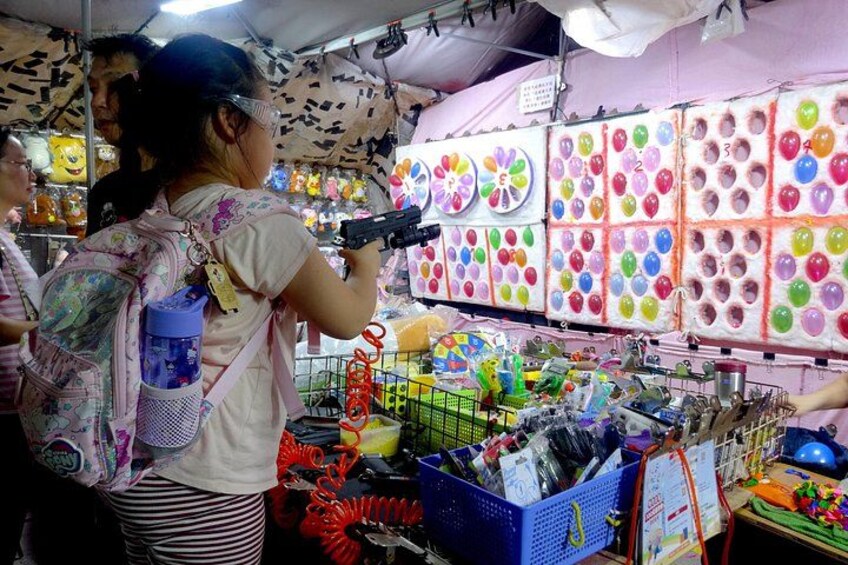 A market stall with colorful balloons and various items for sale. 2