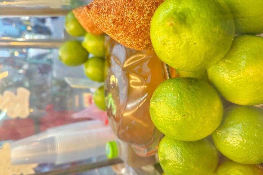 A glass jar filled with green limes and a slice of orange. 2