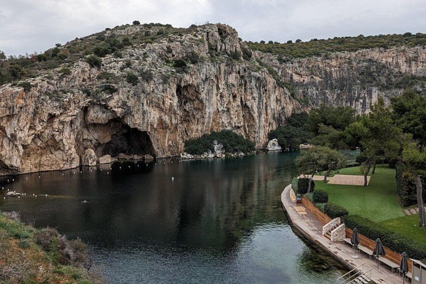 A rocky cliff, a calm lake, and a park with benches and trees. 3