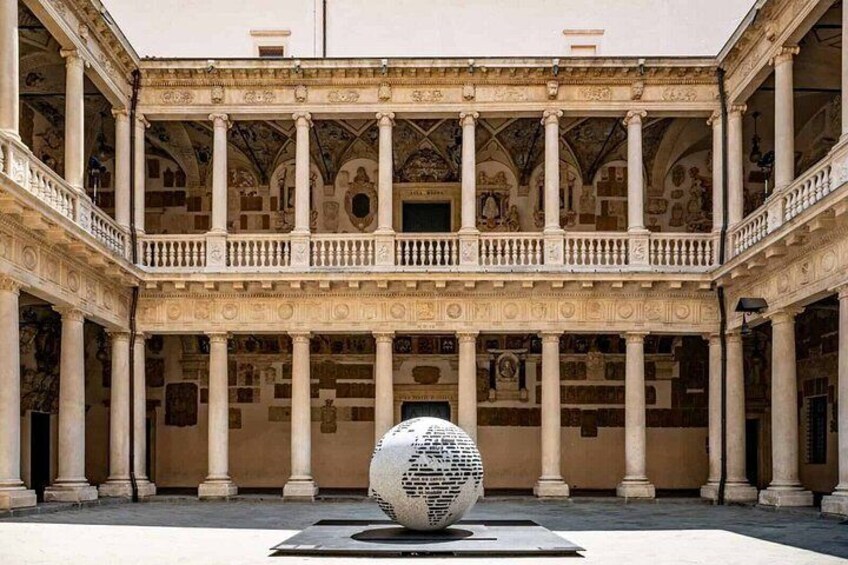 A classical building with a central courtyard, columns, and a spherical sculpture. 3