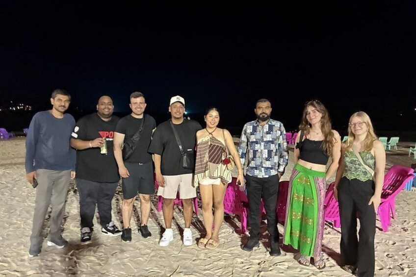 A group of people standing on a sandy beach at night. 5