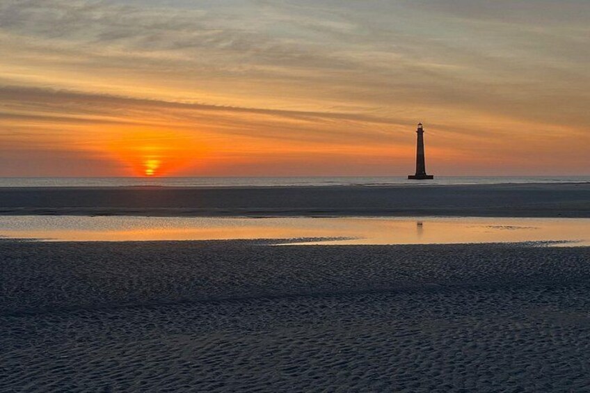 A lighthouse at sunset with a calm beach and ocean. 3