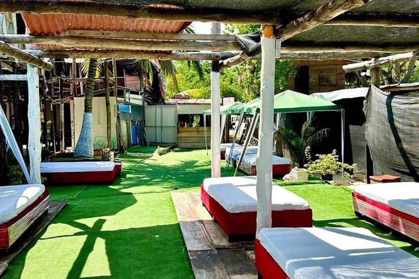 A covered outdoor area with artificial grass, wooden benches, and a green canopy. 4
