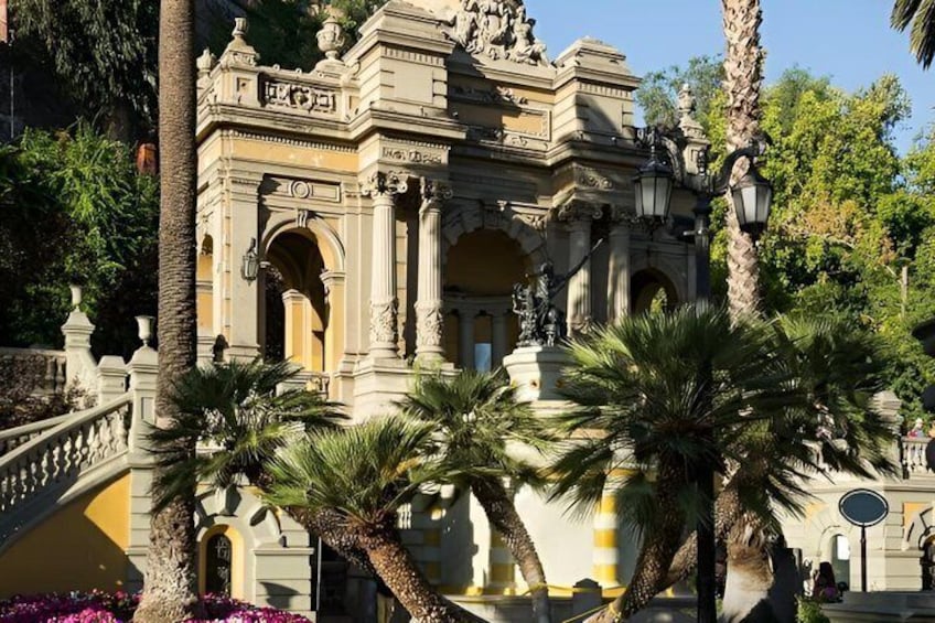 A classical building with ornate columns and statues, surrounded by palm trees and flowers. 5