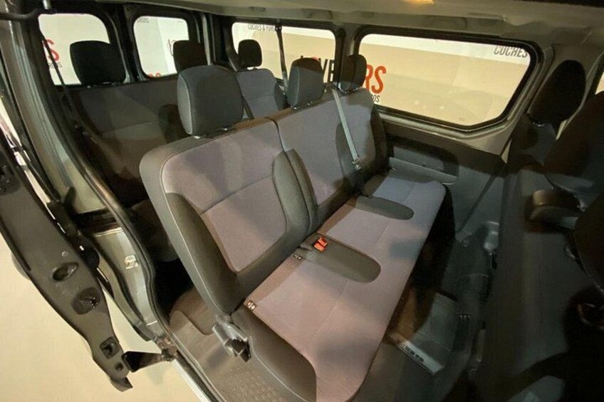 The interior of a vehicle with a bench seat, a door, and a window with text. 5