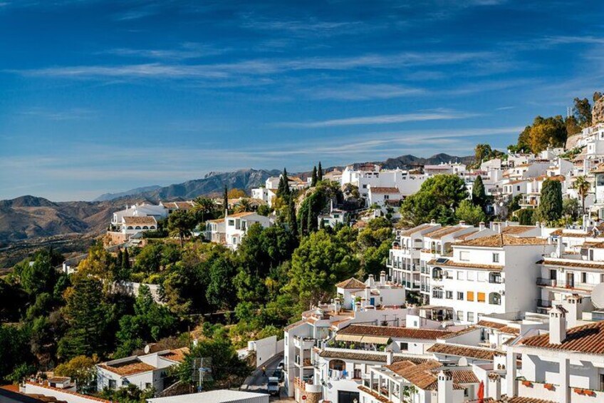 Une ville côtière aux bâtiments blancs, aux collines verdoyantes et au ciel d’un bleu limpide. 2