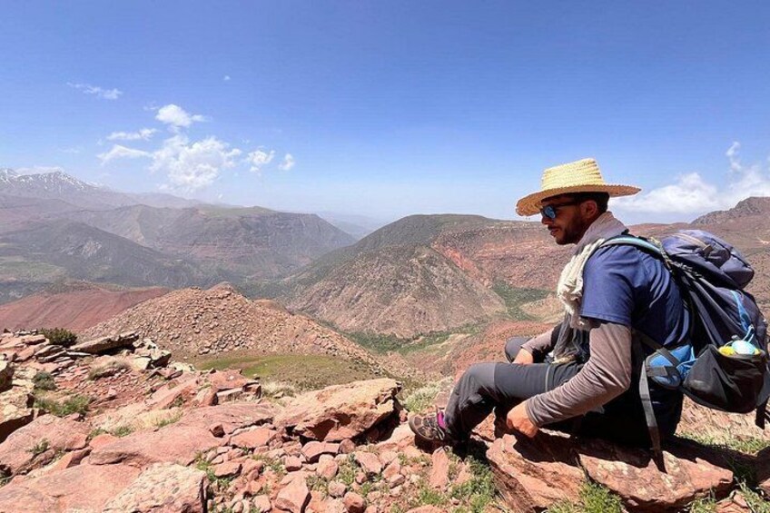 A person sitting on a rocky outcrop overlooking a mountainous landscape. 3