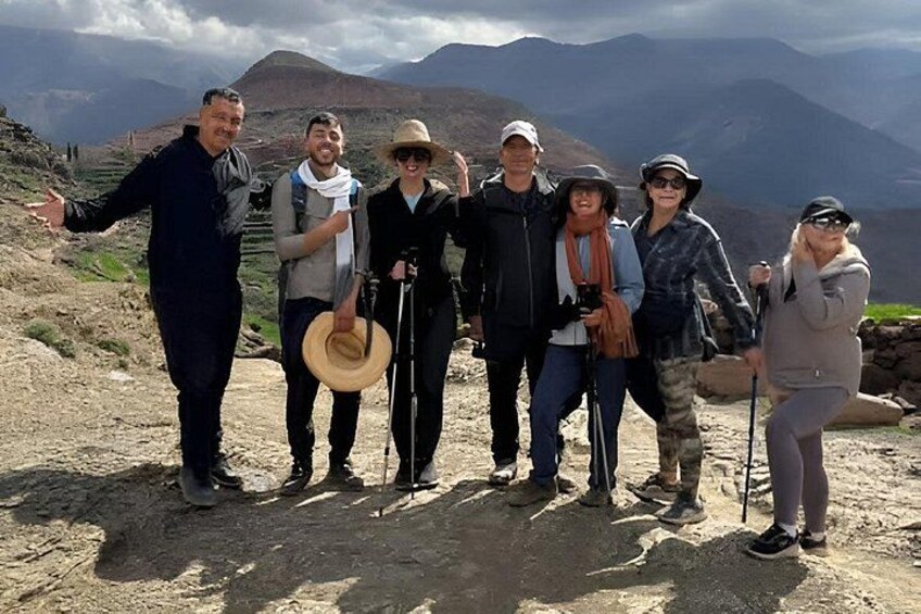 A group of people standing on a rocky outcrop with mountains in the background. 5