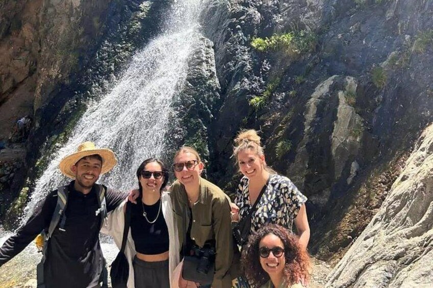 A group of people standing in front of a waterfall. 1