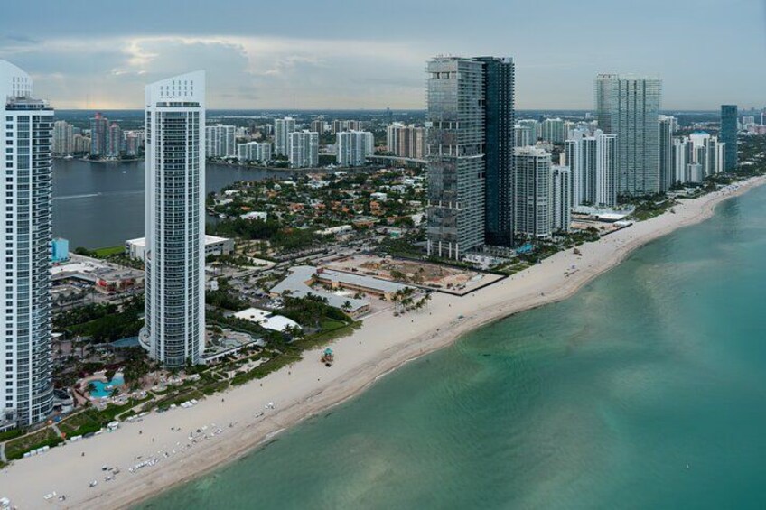 A coastal cityscape with high-rise buildings, a beach, and a body of water. 4