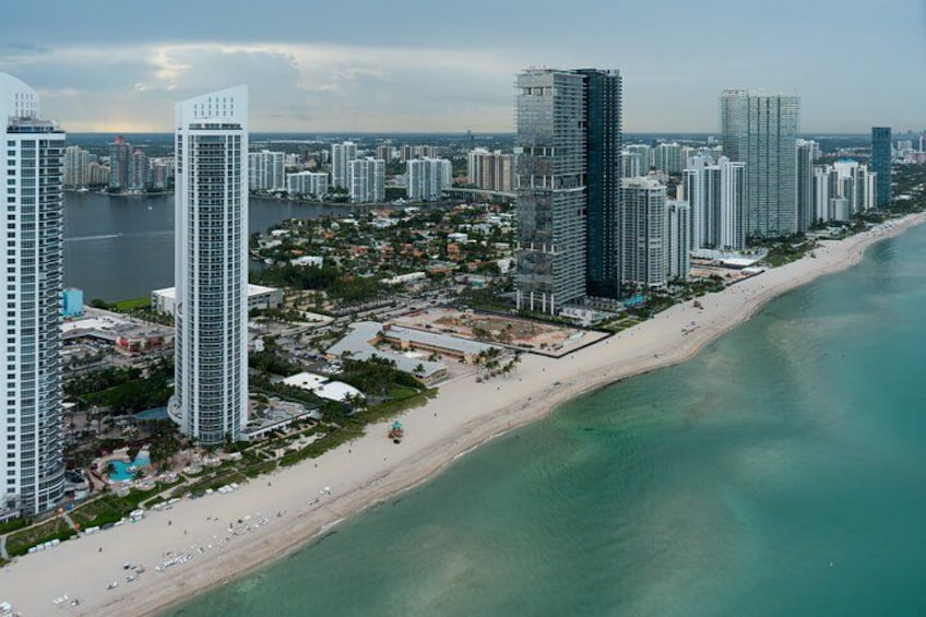 A coastal cityscape with high-rise buildings, a beach, and a body of water. 4