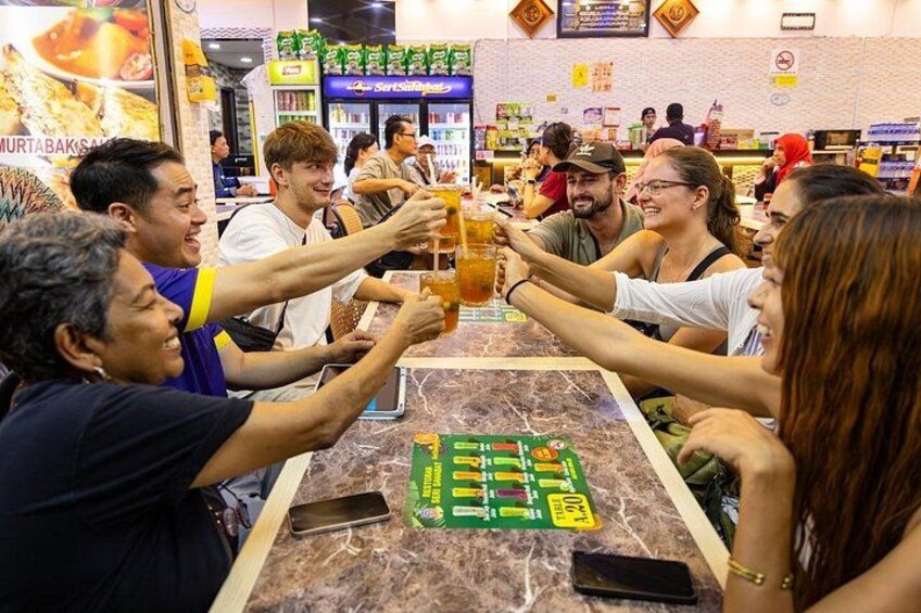 A group of people toasting with drinks at a table in a restaurant. 3