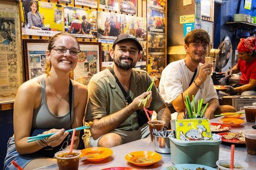 Three people dining at a restaurant with various dishes and utensils on the table. 2