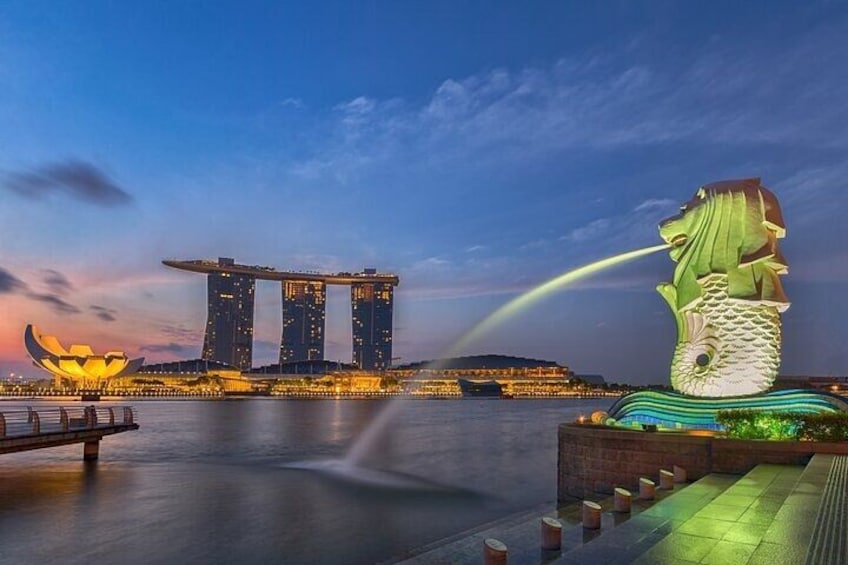Een waterkant met een grote, verlichte sculptuur en het Marina Bay Sands hotel. 4