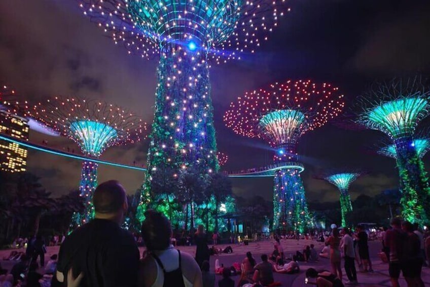 A large illuminated structure with multiple spherical sections, surrounded by people. 3