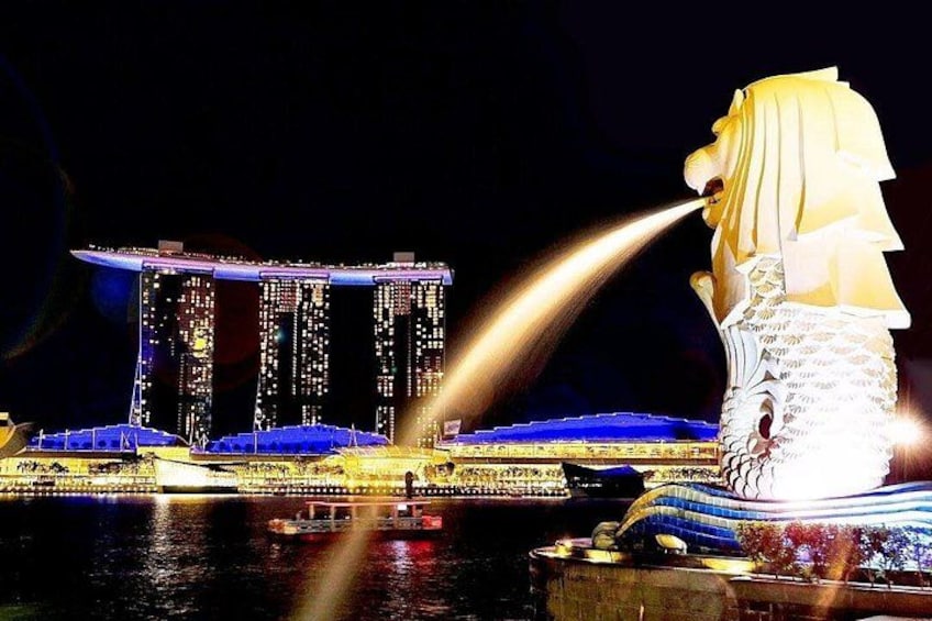 A night scene with a large illuminated statue and the Marina Bay Sands hotel in the background. 3