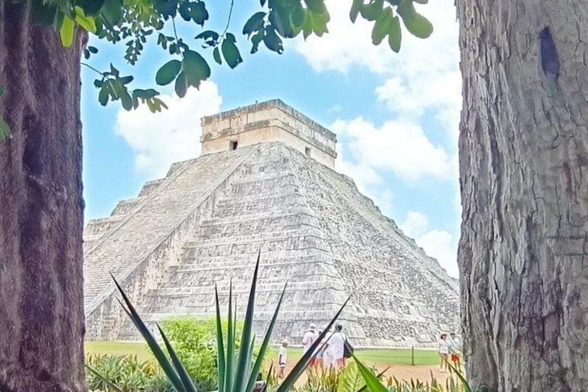 A large pyramid structure with a flat top, surrounded by greenery and trees. 1