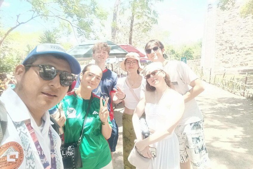 A group of people outdoors, some wearing sports attire, with a car and a stone wall in the background. 5