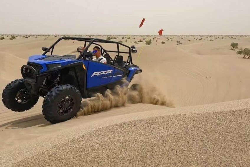 Un veicolo fuoristrada blu che percorre un deserto con dune di sabbia. 2