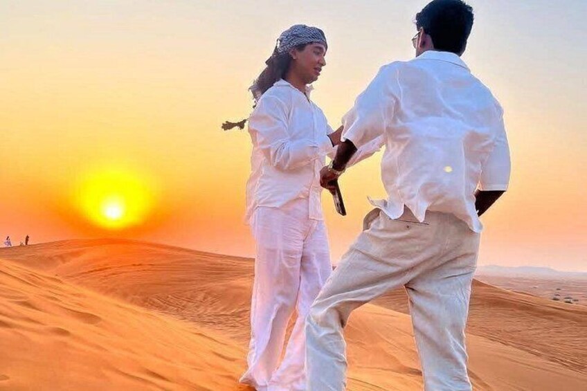 Due persone che ballano in un deserto con un tramonto sullo sfondo. 1