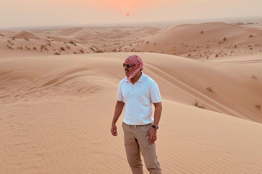 Un uomo in piedi su una duna di sabbia, con un paesaggio desertico sullo sfondo. 5