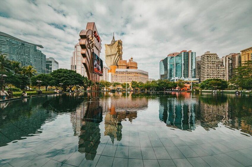 A cityscape with a large body of water reflecting buildings, including a distinctive tower and a domed structure. 2