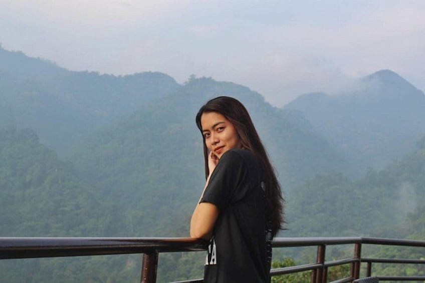A person standing on a balcony overlooking a mountainous landscape. 2