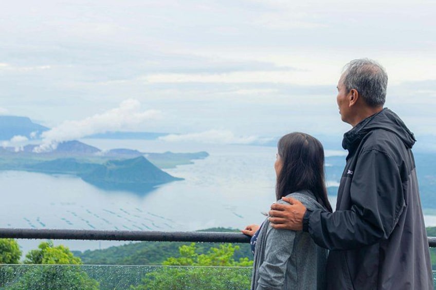 Two people standing by a railing overlooking a body of water with distant landforms. 3