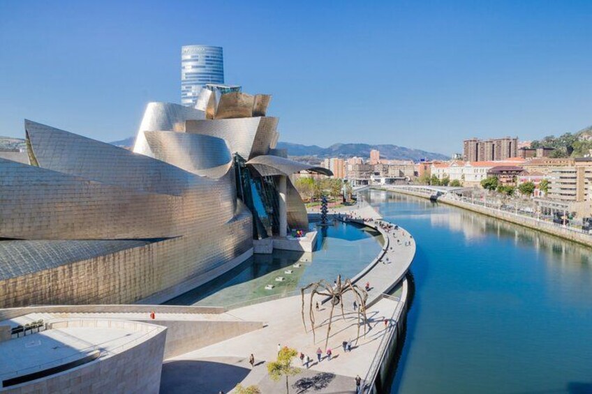 Una estructura arquitectónica moderna con superficie reflectante, un río y cielo despejado. 1