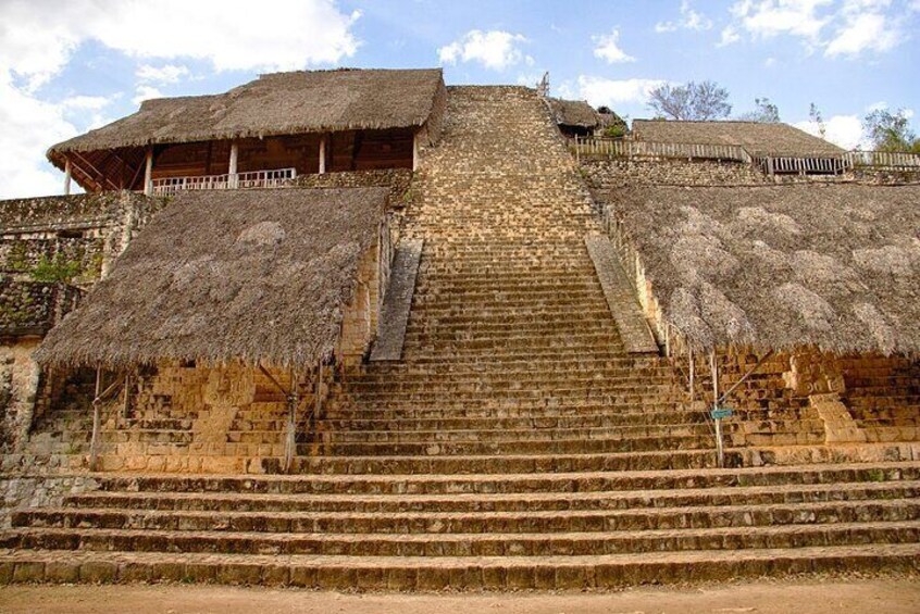 A stone staircase leading up to a thatched-roof structure with a balcony. 3