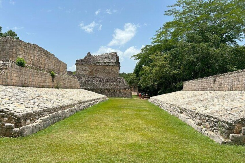 Ancient stone ruins with a central structure and a grassy pathway. 4