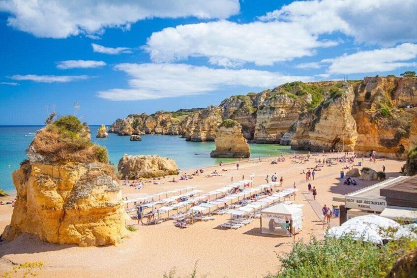 Una spiaggia con scogliere rocciose, acqua cristallina e un bar-ristorante. 5