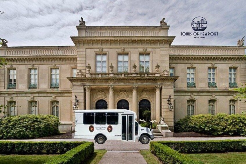 A historic building with a white bus parked in front. 2