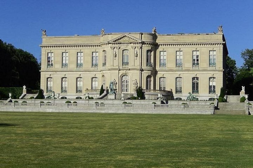 A large, classical building with a symmetrical facade, a central entrance, and a well-maintained lawn in front. 5