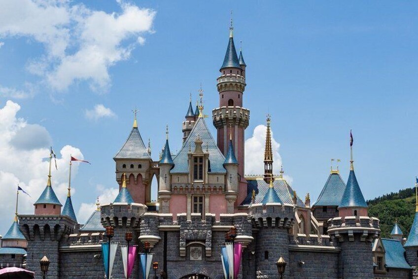 A castle with multiple towers, flags, and a clear blue sky. 1