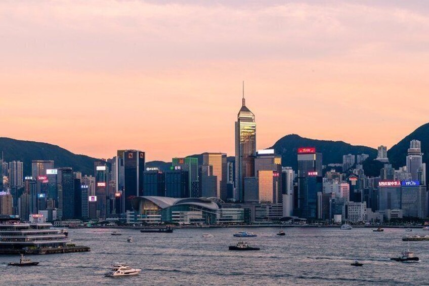 A city skyline with a prominent skyscraper, numerous high-rise buildings, and a body of water with boats. 3