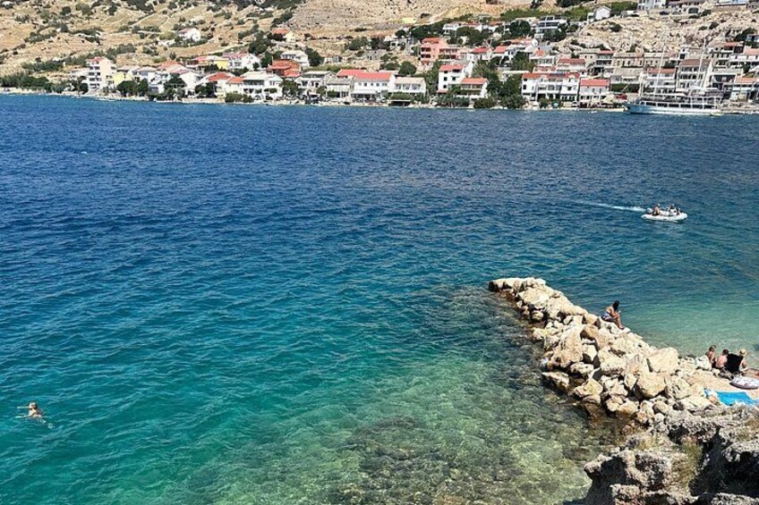 A coastal town with clear blue waters, rocky shoreline, and buildings in the background. 4