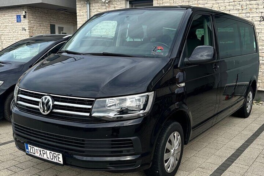A black Volkswagen van parked in a lot. 2