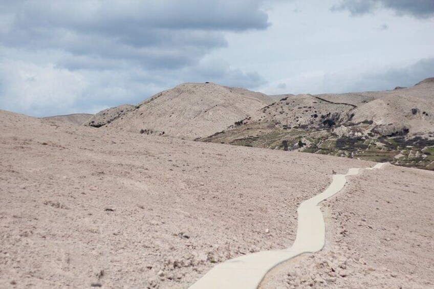 A winding path through a barren landscape with hills in the background. 1