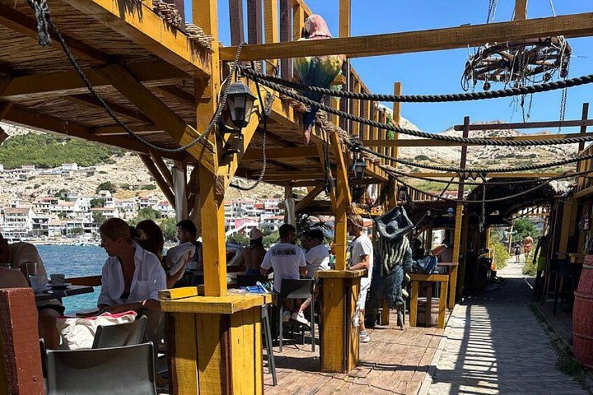 A wooden deck with people dining, a view of a coastal town, and a ropeway. 5