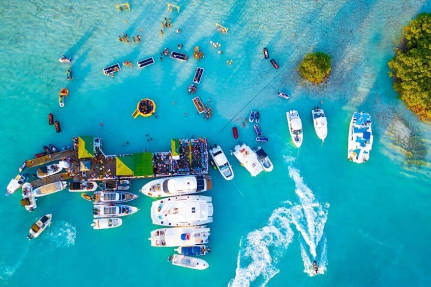 An aerial view of a marina with multiple boats docked and people on the pier. 1